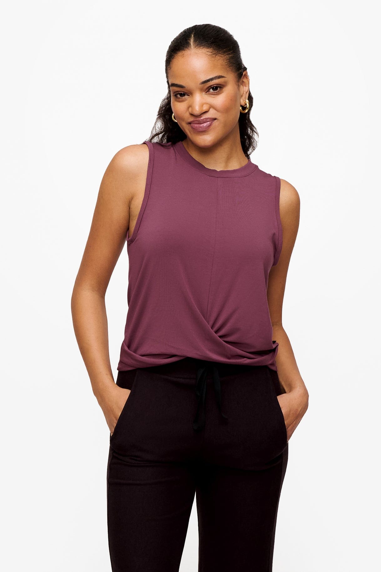 woman wearing a sleeveless shirt with a twist at the front in deep pink with here hands in the pockets