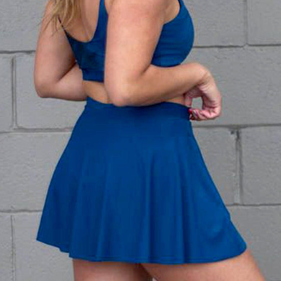 Side of a woman wearing a blue tennis skirt
