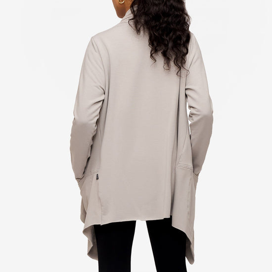 back of a woman wearing a drapey jacket in light grey