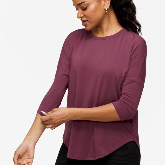 woman wearing a deep pink 3/4 sleeve shirt while looking down
