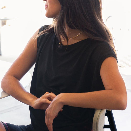 The Box Tee in black is worn by a young woman and paired with tie-dyed bike shorts