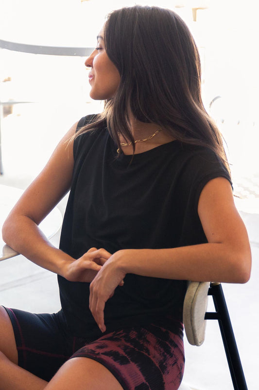 The Box Tee in black is worn by a young woman and paired with tie-dyed bike shorts