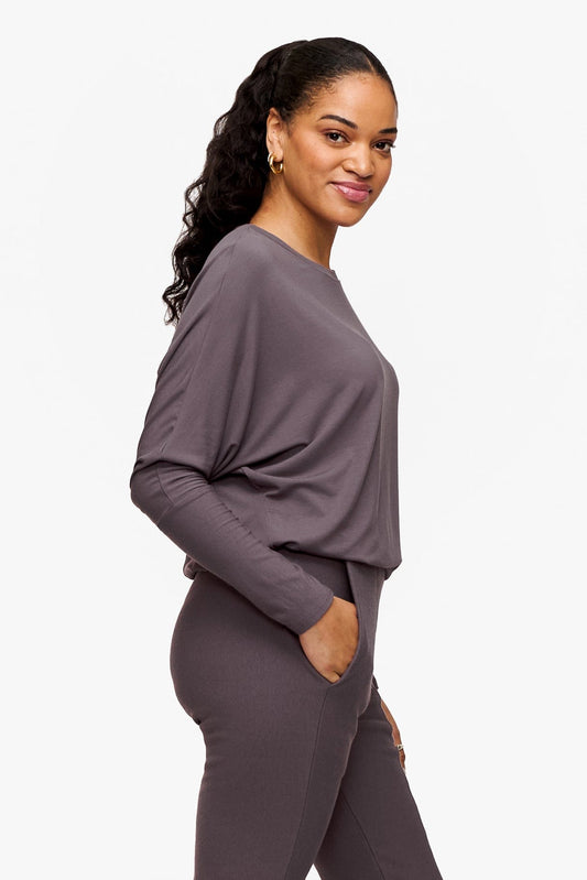 side of a woman wearing a deep purple loose sleeve long sleeve shirt