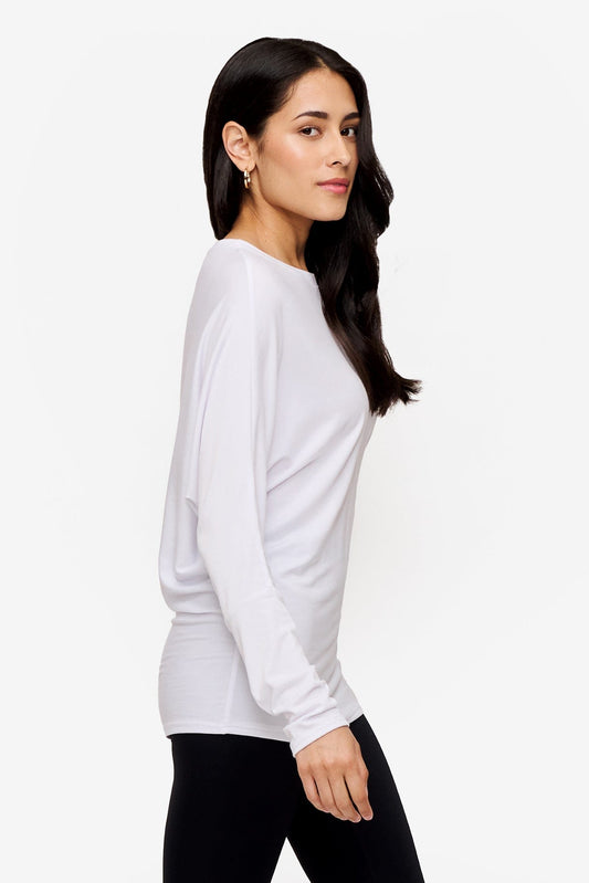 side of a woman wearing a white loose sleeve long sleeve shirt