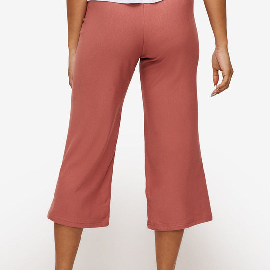 back of a woman wearing orange cropped sweatpants with drawstring 