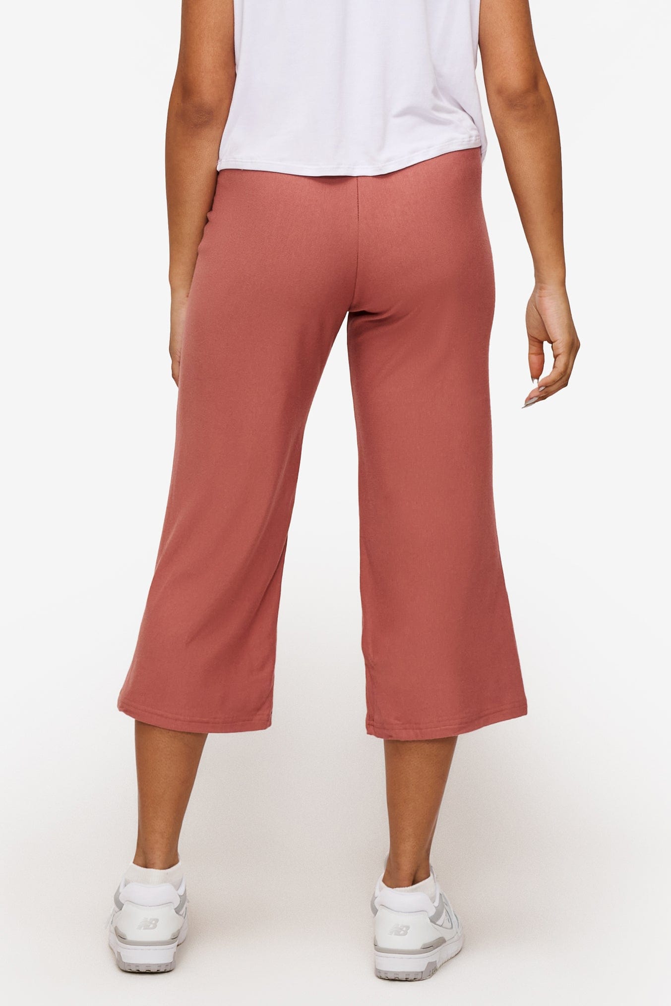 back of a woman wearing orange cropped sweatpants with drawstring 