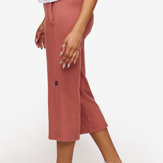side of a woman wearing orange cropped sweatpants with drawstring 