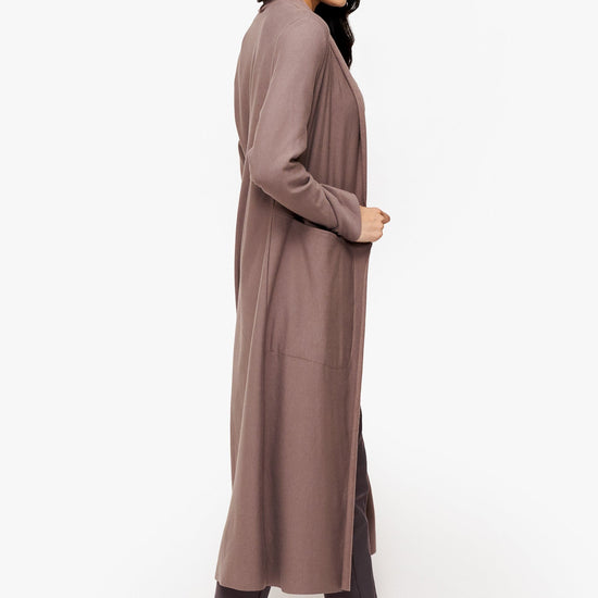 side of a woman wearing a long front open jacket in beige