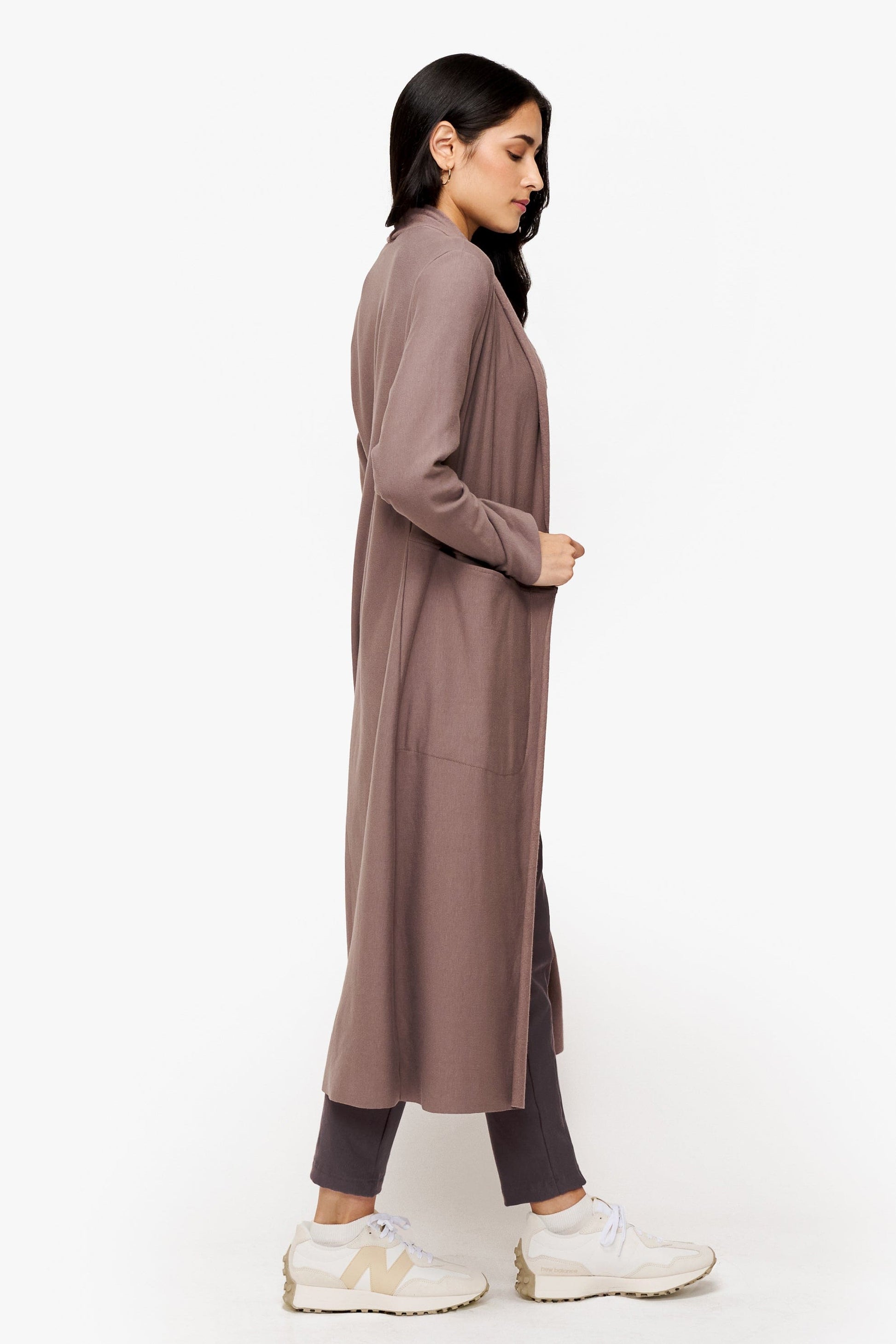 side of a woman wearing a long front open jacket in beige