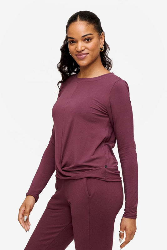 side of a woman wearing a deep pink long sleeve top with twist in the front 