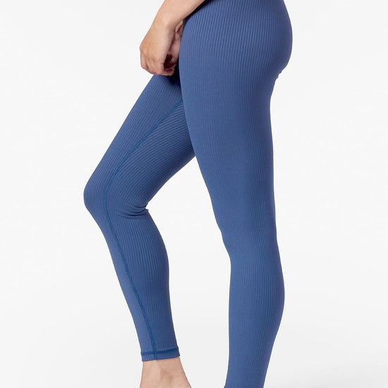 Side of a woman wearing blue ribbed leggings