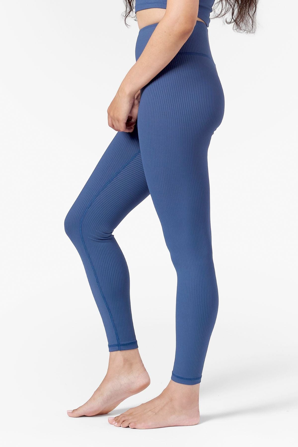Side of a woman wearing blue ribbed leggings