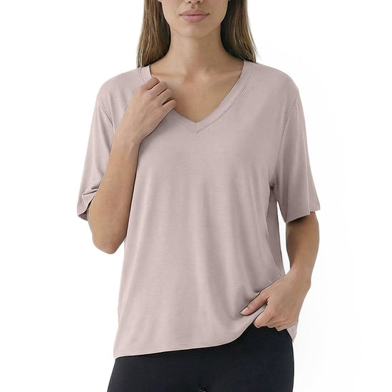 Woman wearing a light pink V-neck top and black leggings on a white background