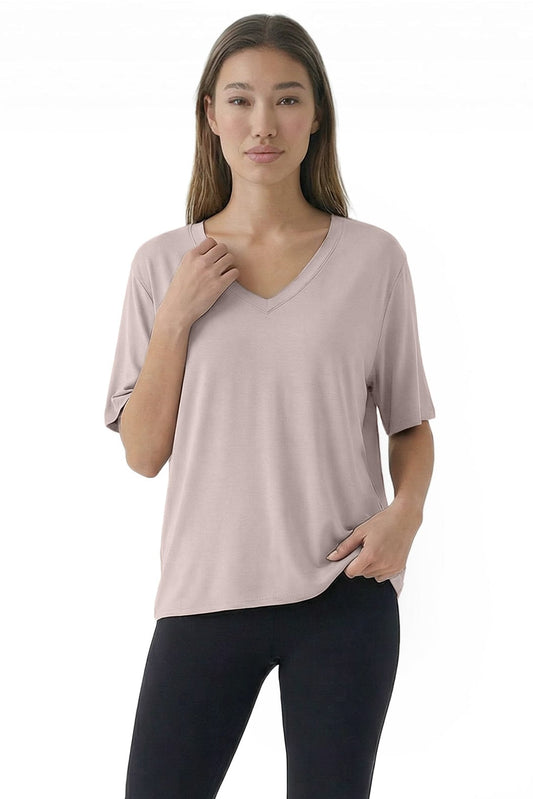 Woman wearing a light pink V-neck top and black leggings on a white background