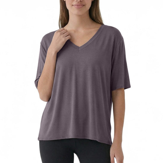 Woman wearing a purple V-neck t-shirt and black leggings on a white background