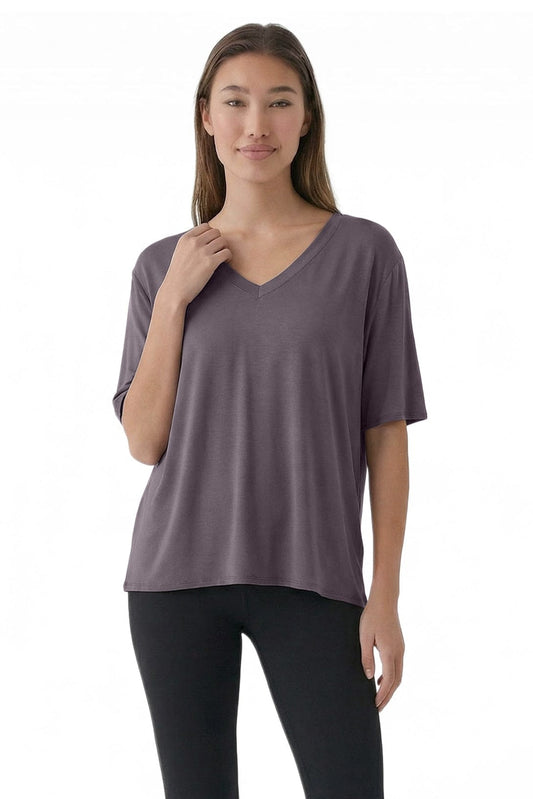 Woman wearing a purple V-neck t-shirt and black leggings on a white background