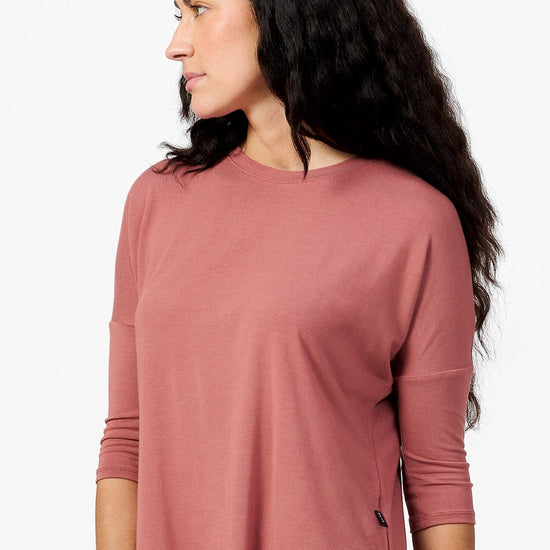 Side of a woman wearing a light rust 3/4 length sleeve shirt