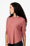 Side of a woman wearing a light rust 3/4 length sleeve shirt