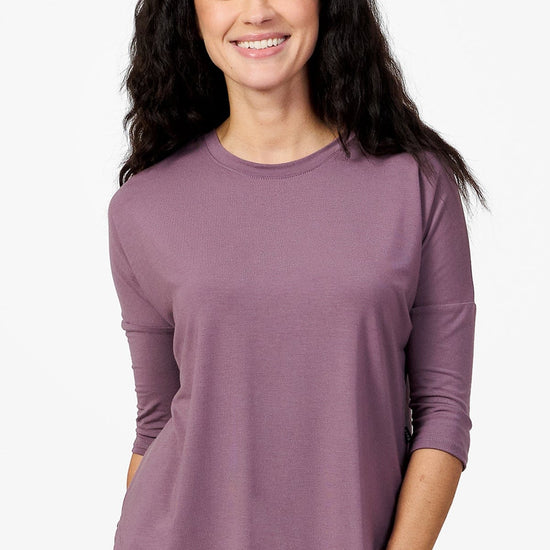 woman smiling wearing a light purple 3/4 length sleeve shirt