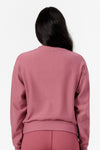 Back of a woman wearing pink crew neck sweatshirt