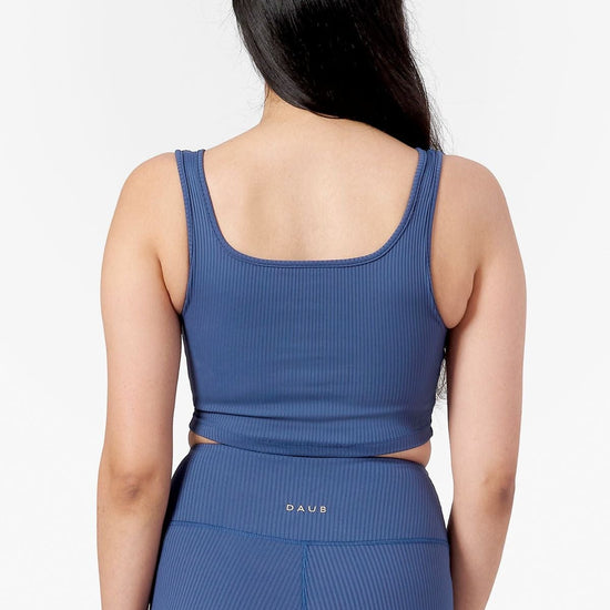 Back of a woman wearing square side of a reversible ribbed sports bra in blue