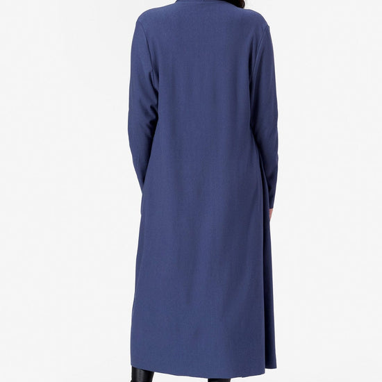 The back view of a woman with dark hair wearing a straight long jacket made in Canada out of bamboo cotton fleece.
