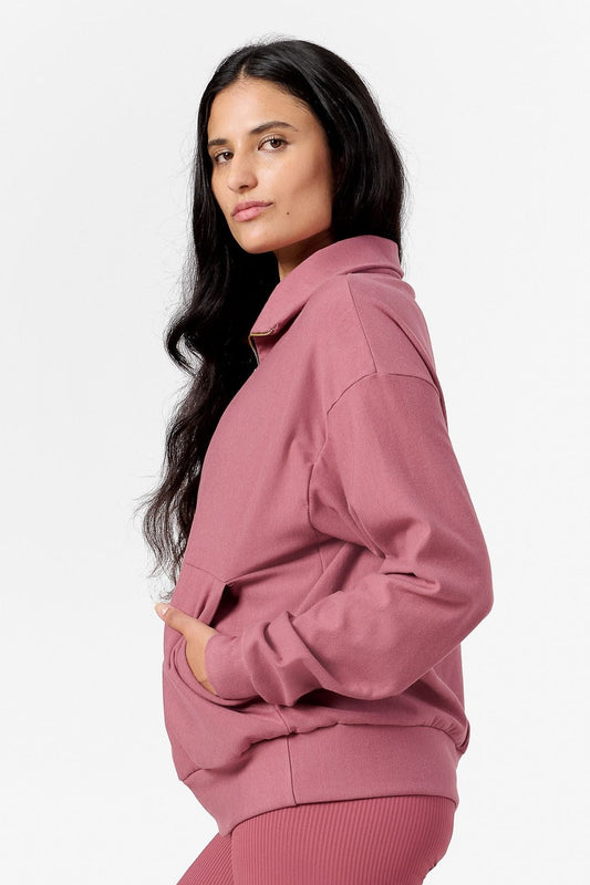 Side of a woman wearing a pink half zip sweatshirt