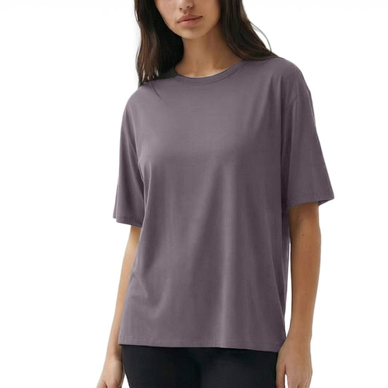 Woman wearing a purple t-shirt and black pants on a white background