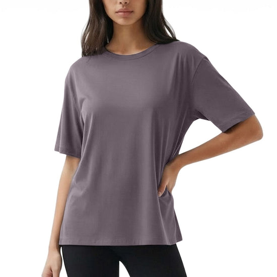 Woman wearing a loose-fitting purple t-shirt and black pants on a white background