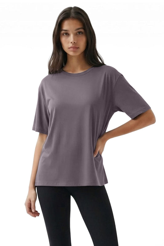 Woman wearing a loose-fitting purple t-shirt and black pants on a white background