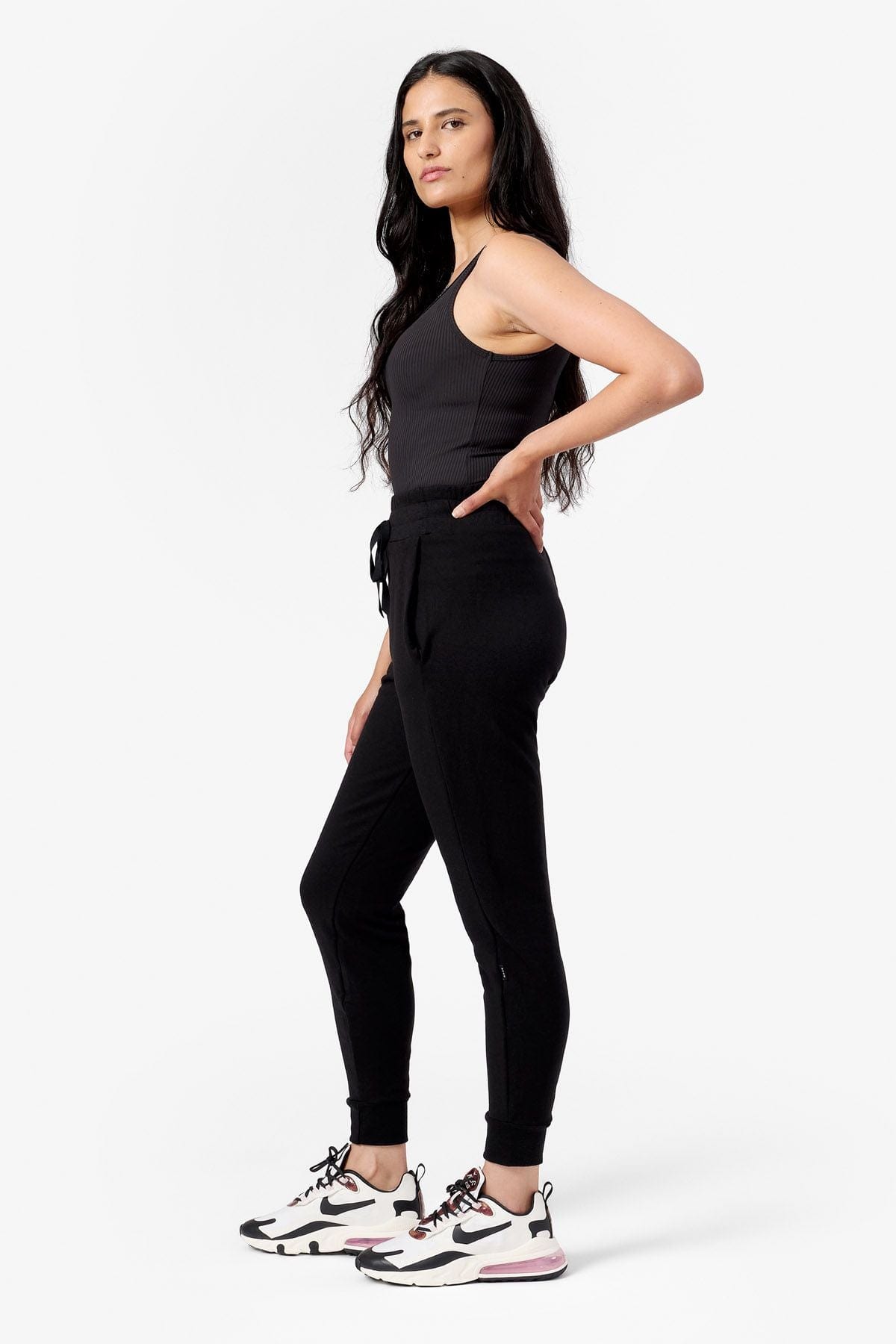 side view of a woman wearing black fleece joggers and a black tank top