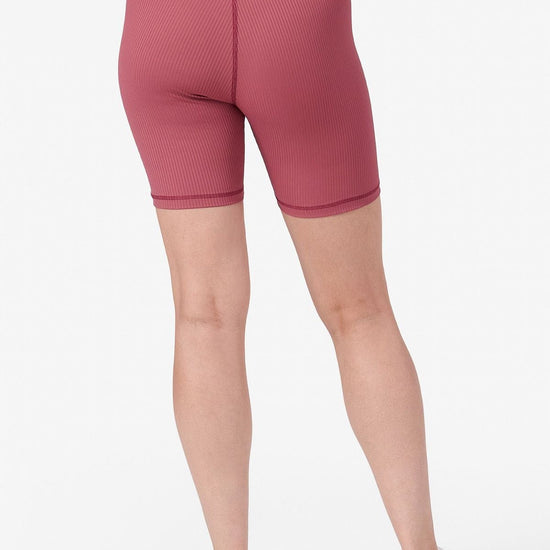 half view of a woman wearing pink ribbed bike shorts from the back