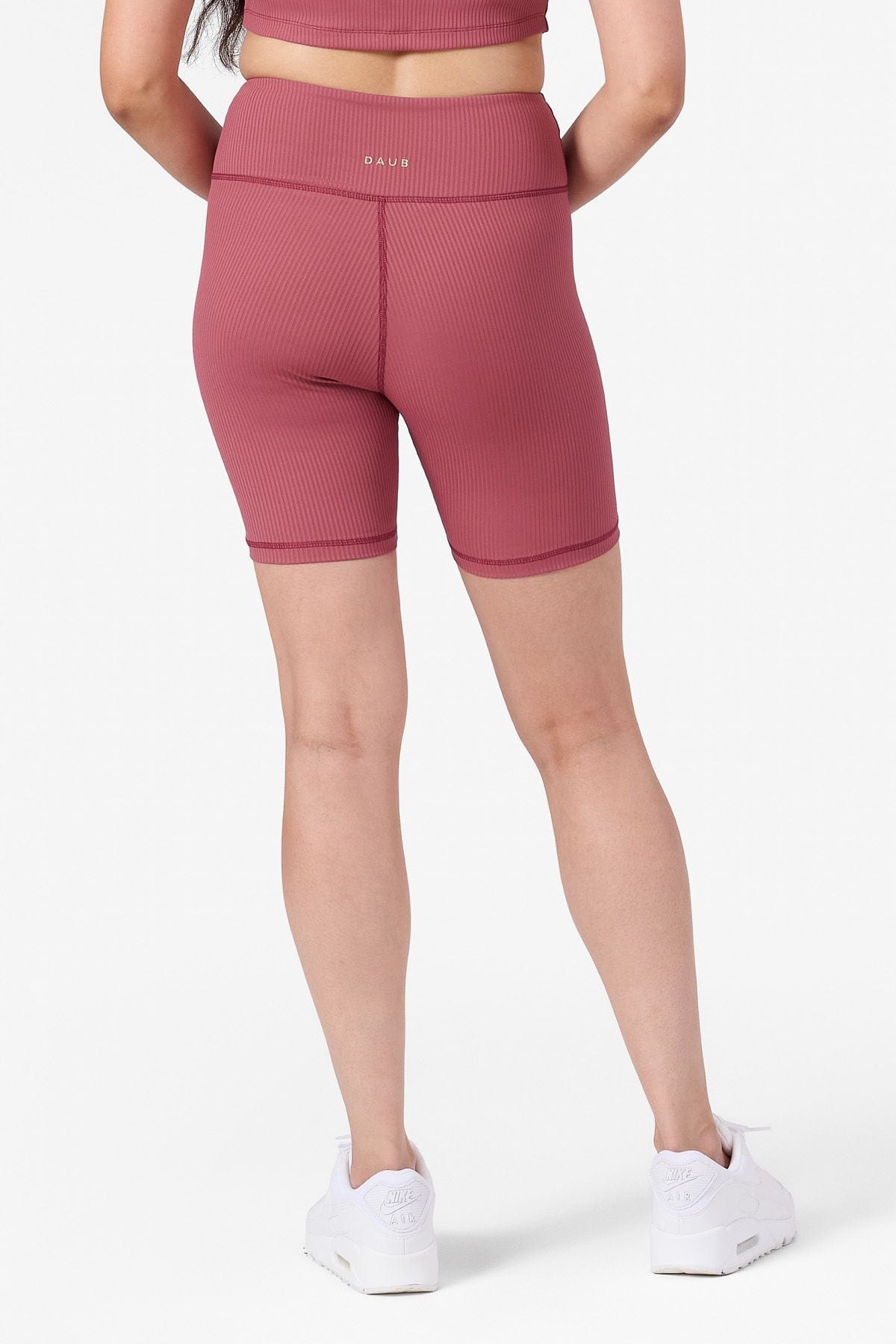 half view of a woman wearing pink ribbed bike shorts from the back