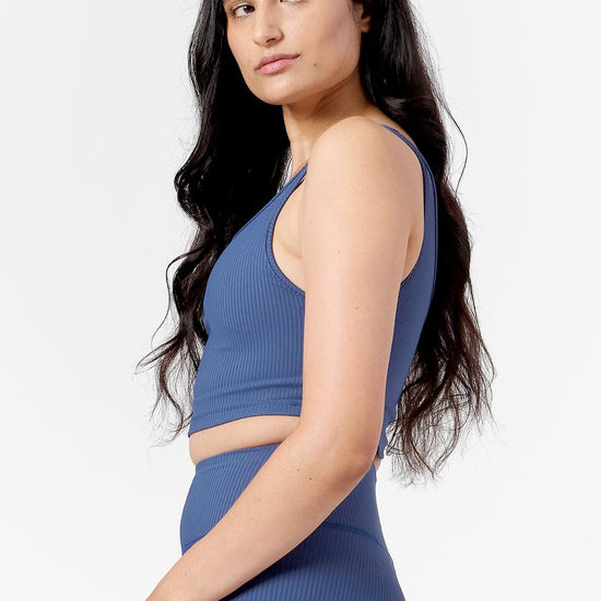 woman looking over her shoulder wearing a matching blue ribbed crop top and blue ribbed leggings