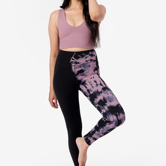 a woman doing yoga wearing a pink sports bra and pink and black tie dye leggings