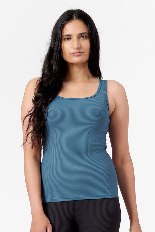 a woman wearing a teal, ribbed reversible tank top with a square neck line which is hip length 