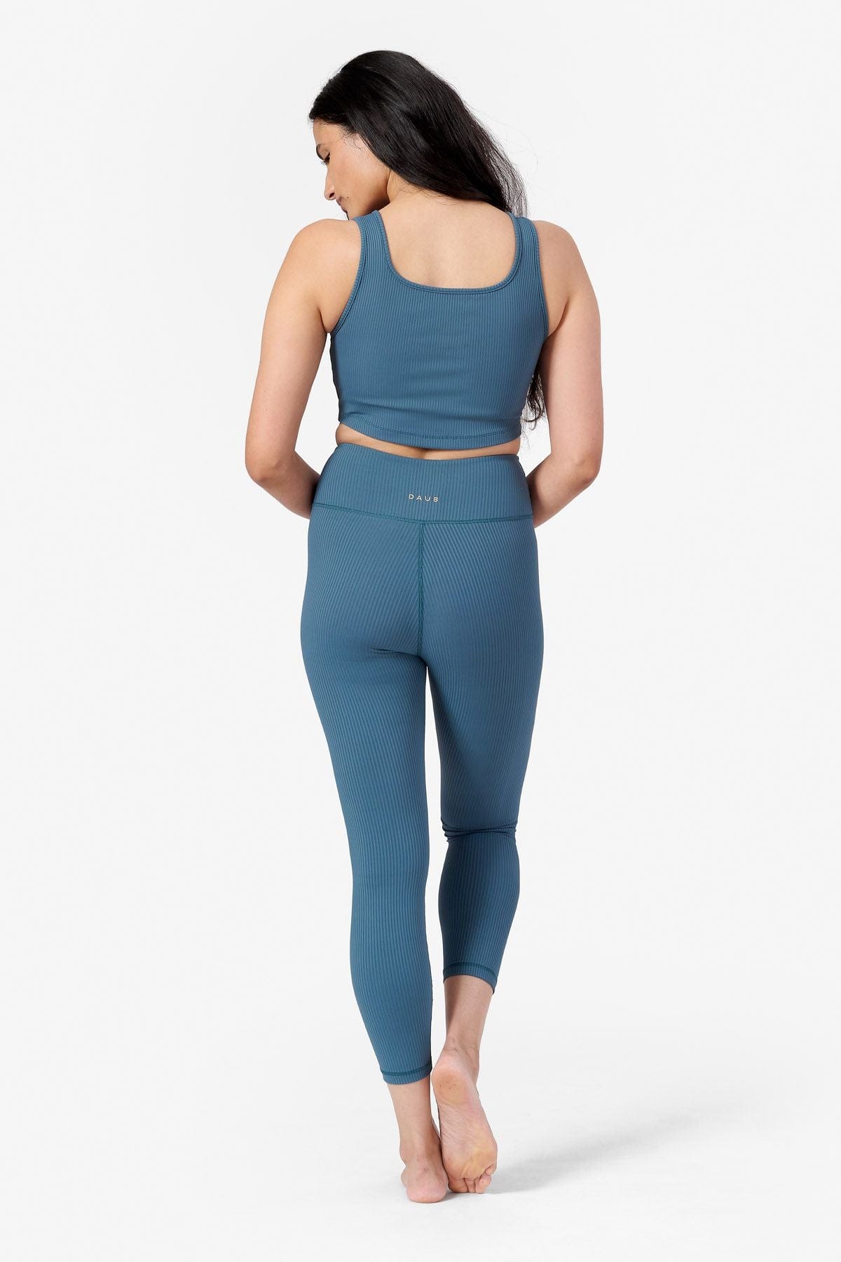 back of woman wearing a ribbed teal bra and teal yoga leggings