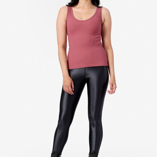 a woman wearing a ribbed pink tank top with black shiny leggings