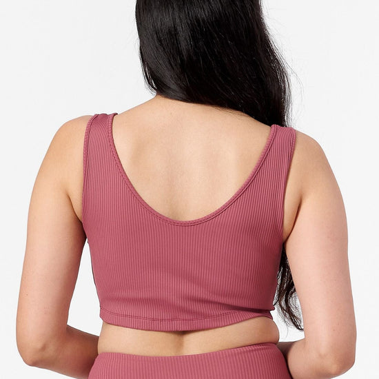 back of woman wearing reversible ribbed crop top in pink with round scoop side