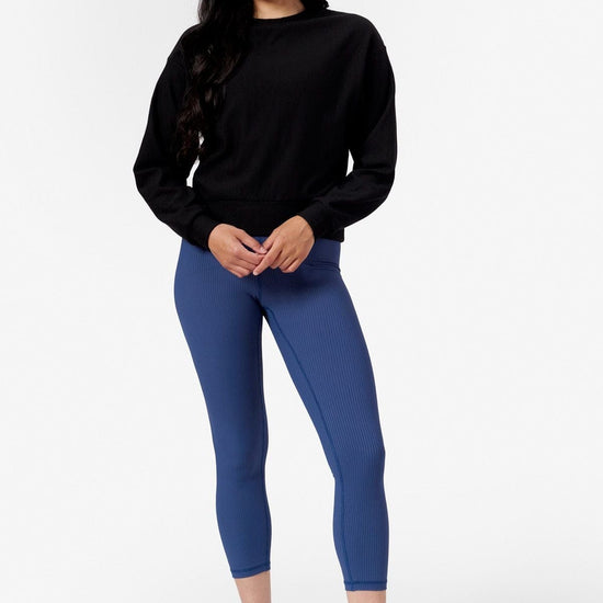 Woman wearing a black crew neck sweatshirt and Blue leggings