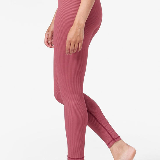 side view of a woman wearing pink ribbed leggings which are ankle length 