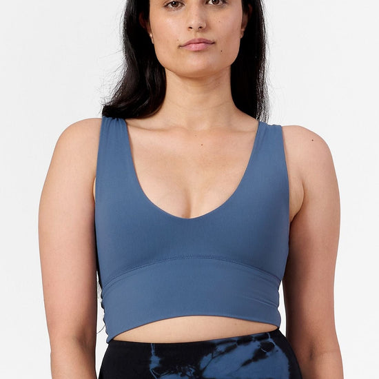  a woman wearing a low cut crop top in blue with tie dye blue and black leggings
