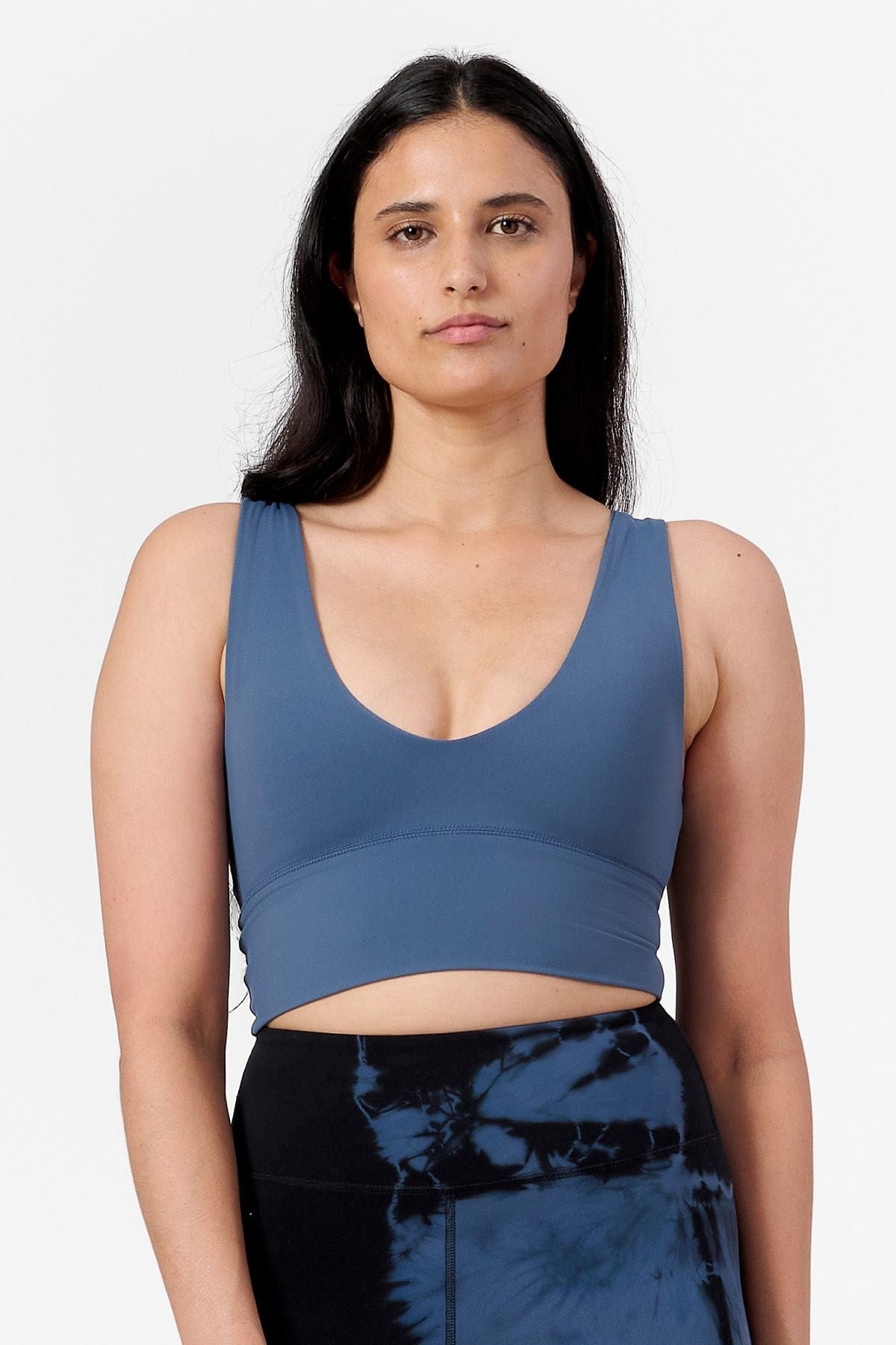  a woman wearing a low cut crop top in blue with tie dye blue and black leggings