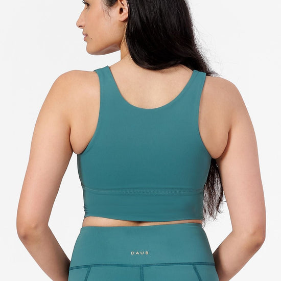 a woman wearing a teal high neck crop top with matching teal shorts