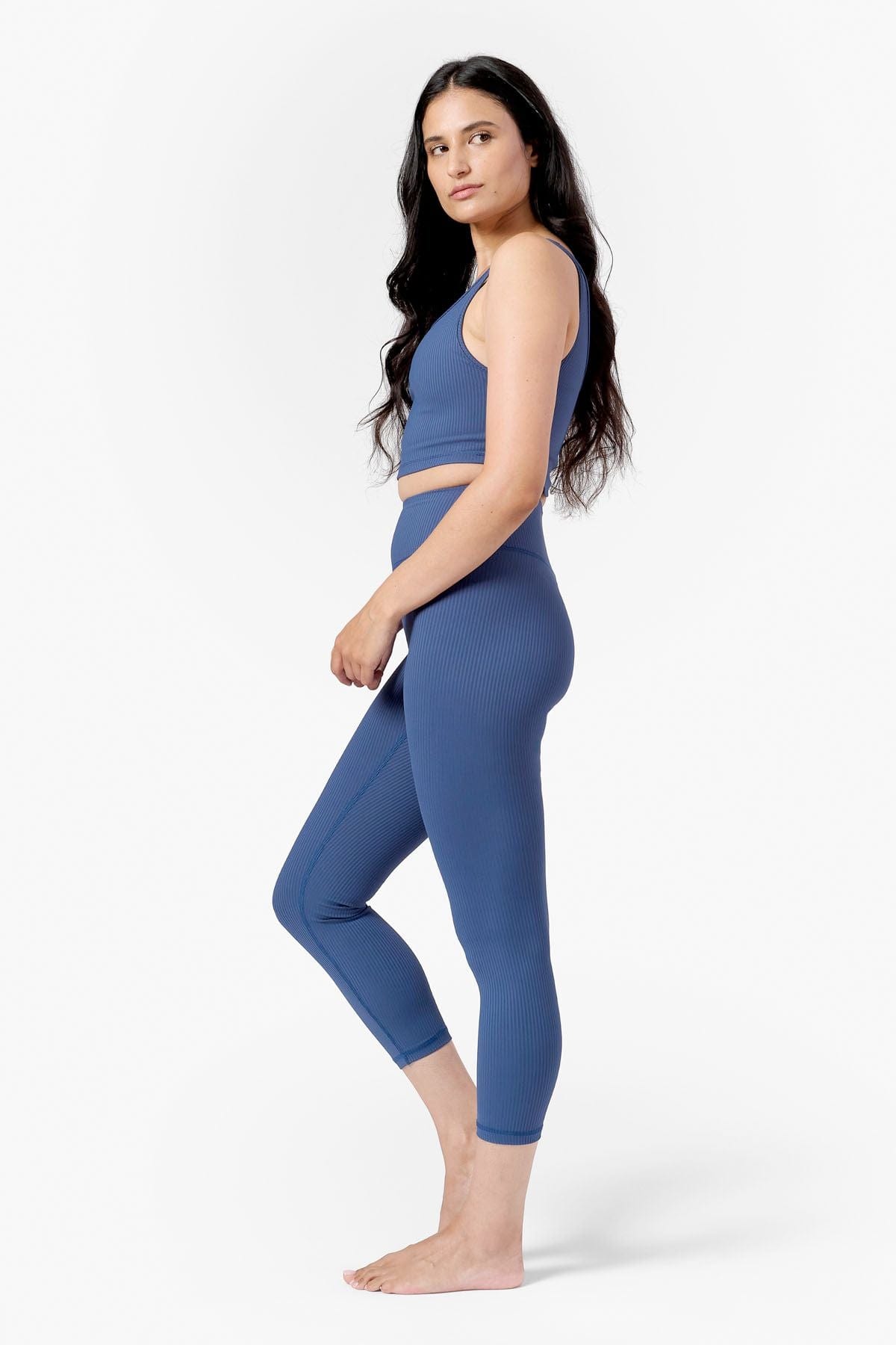 a woman's side view wearing a blue ribbed sports bra and blue ribbed mid length legging
