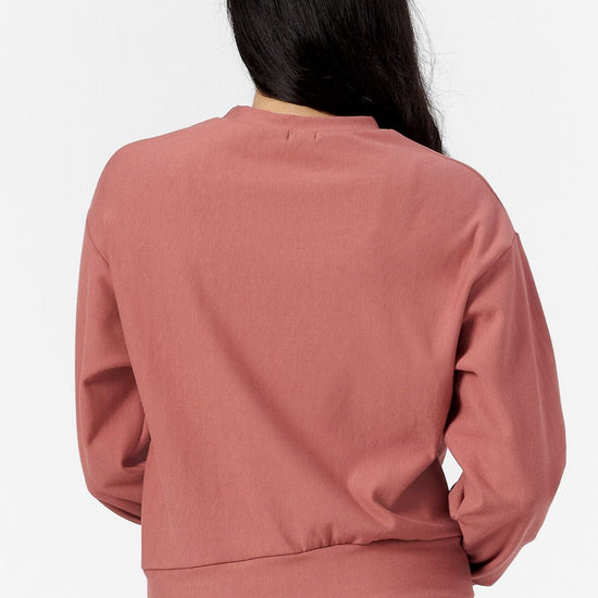 Back of a woman wearing a light rust crew neck