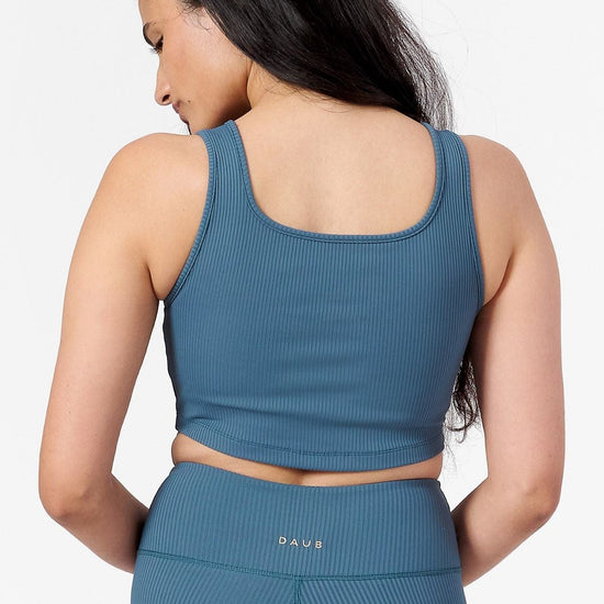 back of a woman wearing a square neck line sports bra with matching ribbed teal leggings