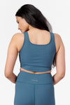 back of a woman wearing a square neck line sports bra with matching ribbed teal leggings