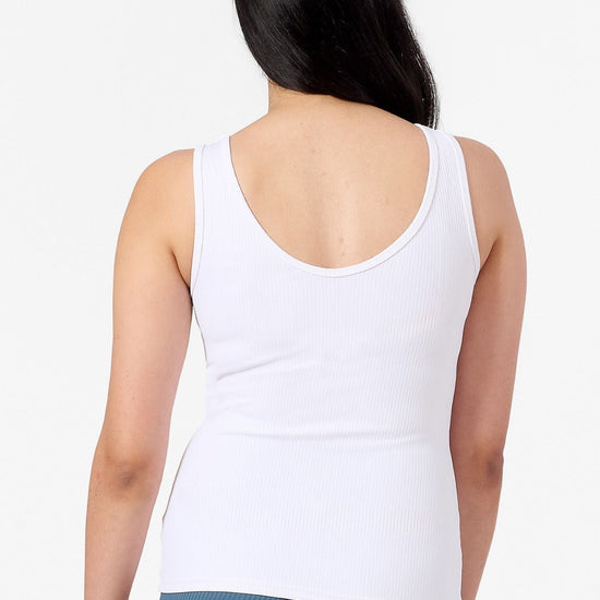 back of a woman wearing a white ribbed sports top and blue leggings 