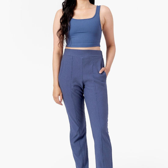 a woman wearing blue straight leg faux pleated pants with blue ribbed square neck tank top